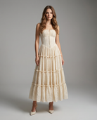Woman wearing a beige strapless dress with ruffled layers on a gray background