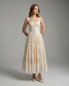 Woman wearing a white tiered dress against a gray background